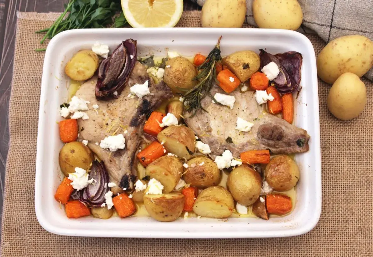 Chuletas de cerdo al horno con patatas, zanahorias, cebolla morada y queso feta. Un plato sabroso y completo.