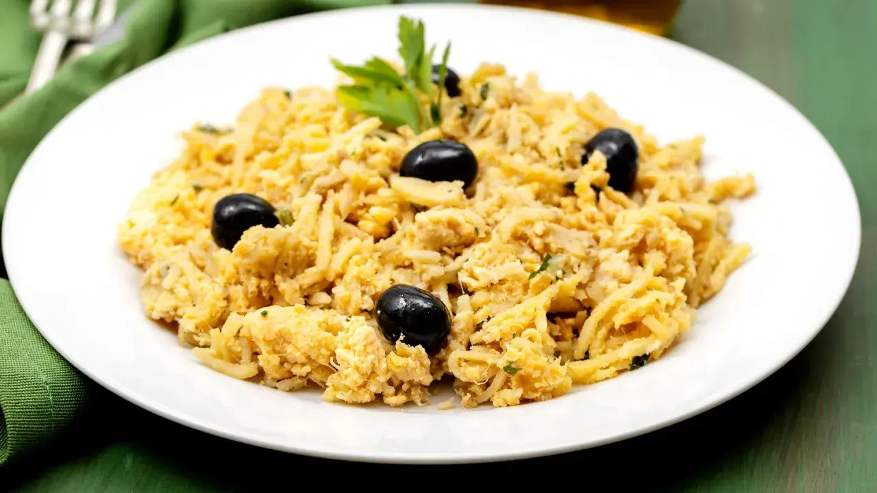 Delicioso bacalao a bras, un plato tradicional portugués con patatas finas, huevo y aceitunas negras, adornado con perejil fresco.