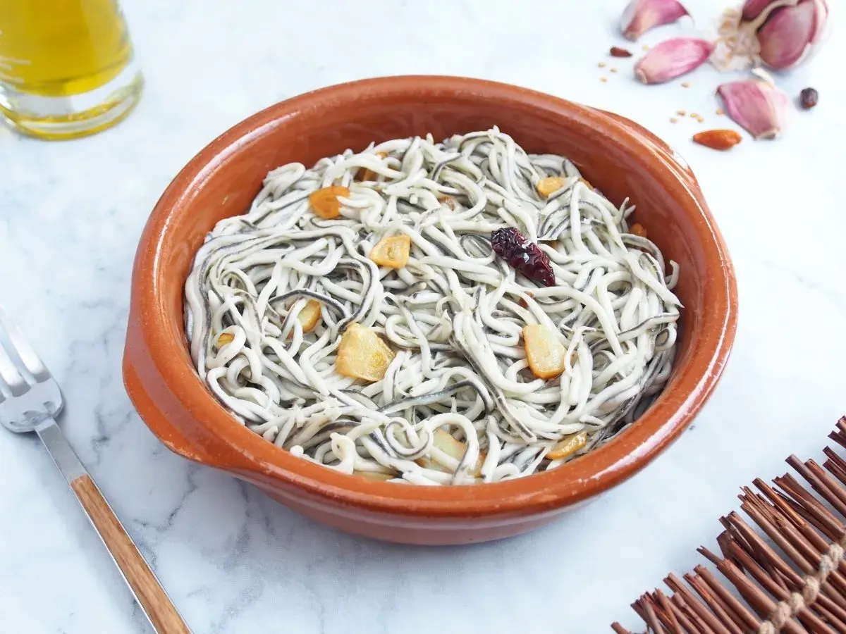 Deliciosas gulas al ajillo en cazuela de barro, con láminas de ajo dorado y un toque picante.