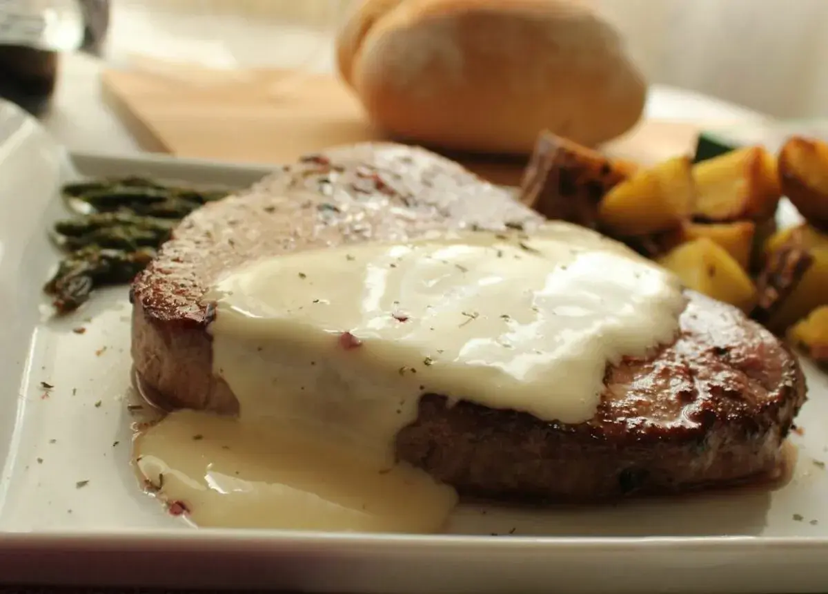 Tierna ternera en salsa cremosa, acompañada de espárragos y patatas asadas. Un plato principal delicioso.