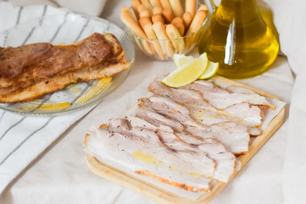 Chicharrón de Cádiz, lonchas de panceta asada, palitos de pan y limón, todo listo para disfrutar.