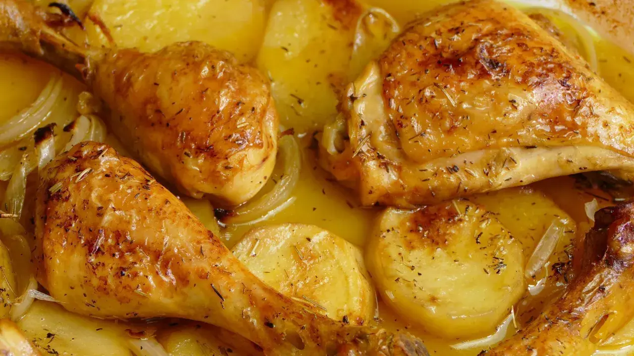 Pollo al horno con patatas, dorado y jugoso, con hierbas aromáticas y cebolla. Un plato casero irresistible.
