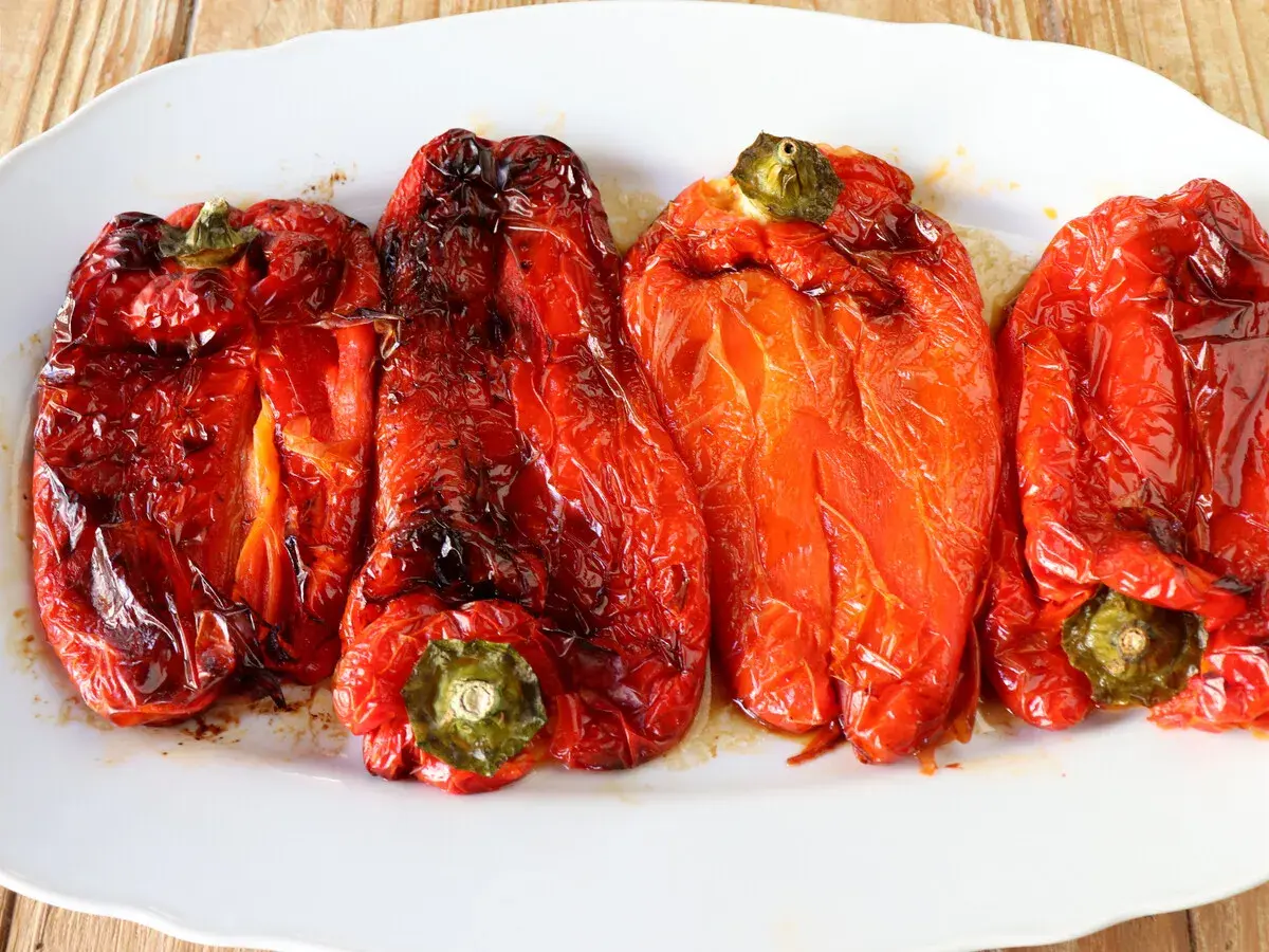 Pimientos rojos asados en freidora de aire, con piel arrugada y un brillo apetitoso.