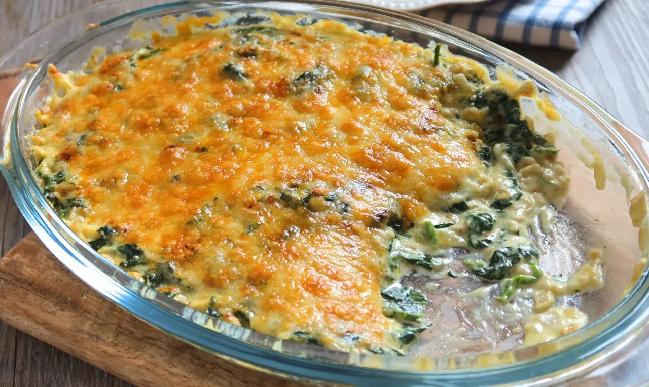 Delicioso plato de espinacas a la crema, gratinado con queso dorado y burbujeante, listo para servir.