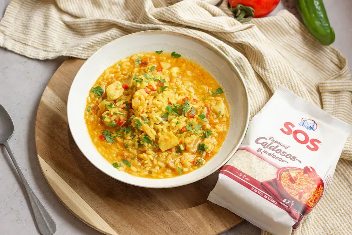 Un plato de arroz con bacalao, pimientos y perejil, acompañado de un paquete de arroz SOS especial caldosos.
