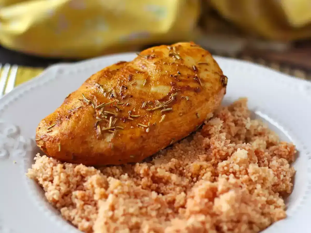 Pechuga de pollo dorada y jugosa, cocinada en freidora de aire, servida sobre una cama de cuscús.