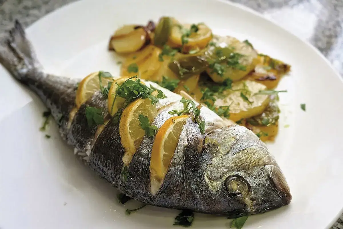 Dorada al horno con rodajas de lim&oacute;n y perejil fresco, acompa&ntilde;ada de patatas asadas. Un plato delicioso y saludable.