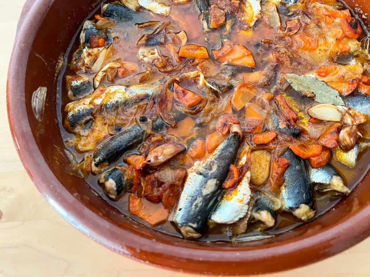 Sardinas en escabeche, con zanahoria y laurel, listas para disfrutar en una cazuela de barro.