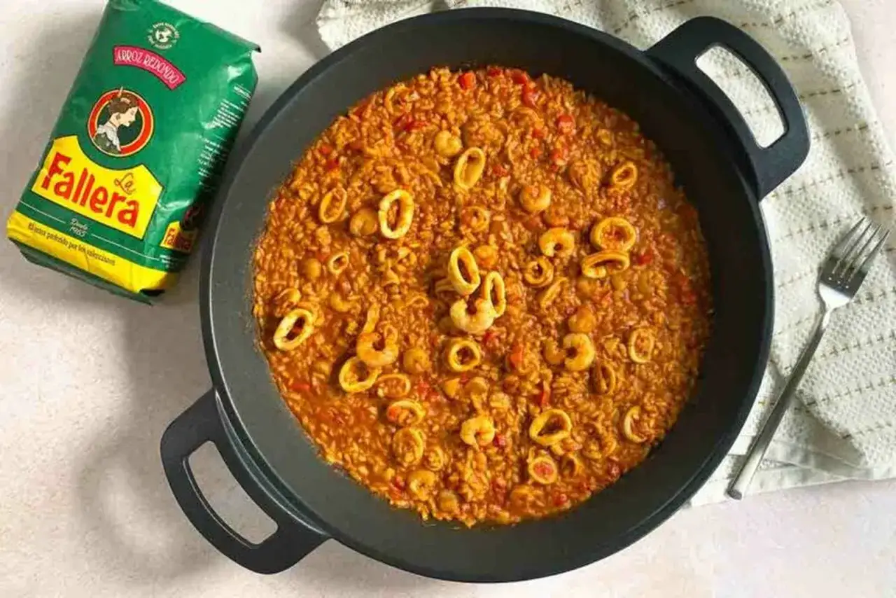 Arroz con calamares y gambas en paellera, junto a un paquete de arroz Fallera. &iexcl;Un plato delicioso!