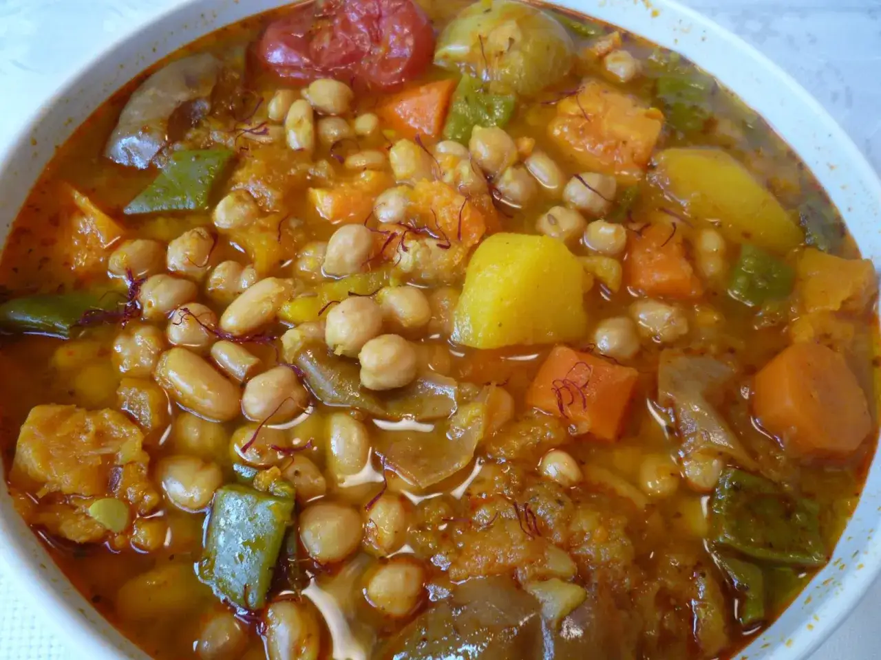 Un plato humeante de olla gitana murciana, rebosante de garbanzos, patatas, zanahorias, pimientos y tomate, con hebras de azafrán.