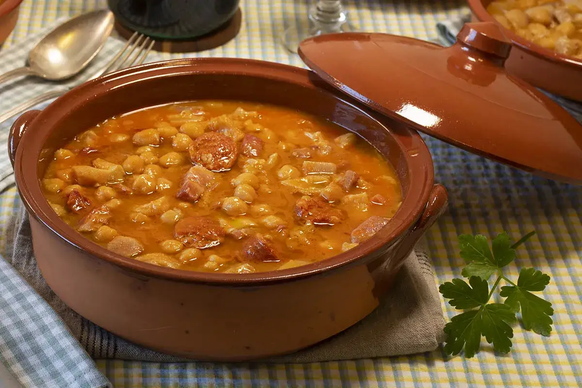 Un reconfortante plato de callos con garbanzos, trozos de chorizo y panceta en una cazuela de barro.