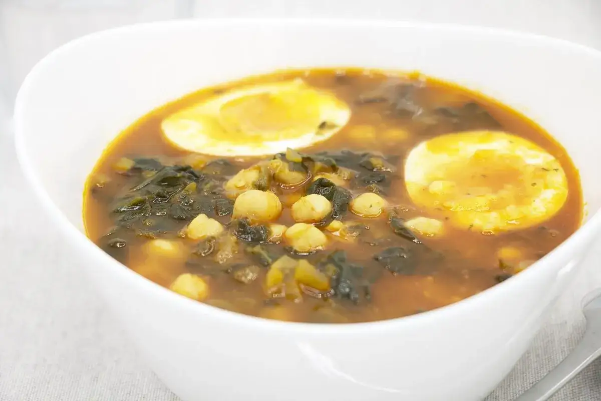 Un plato humeante de garbanzos con espinacas y huevo duro, una deliciosa receta de garbanzos tradicional.
