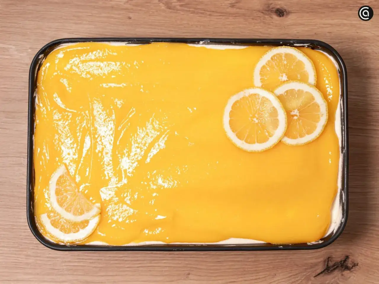 Tiramis&uacute; de lim&oacute;n reci&eacute;n hecho, cubierto con una crema amarilla brillante y decorado con rodajas de lim&oacute;n fresco.