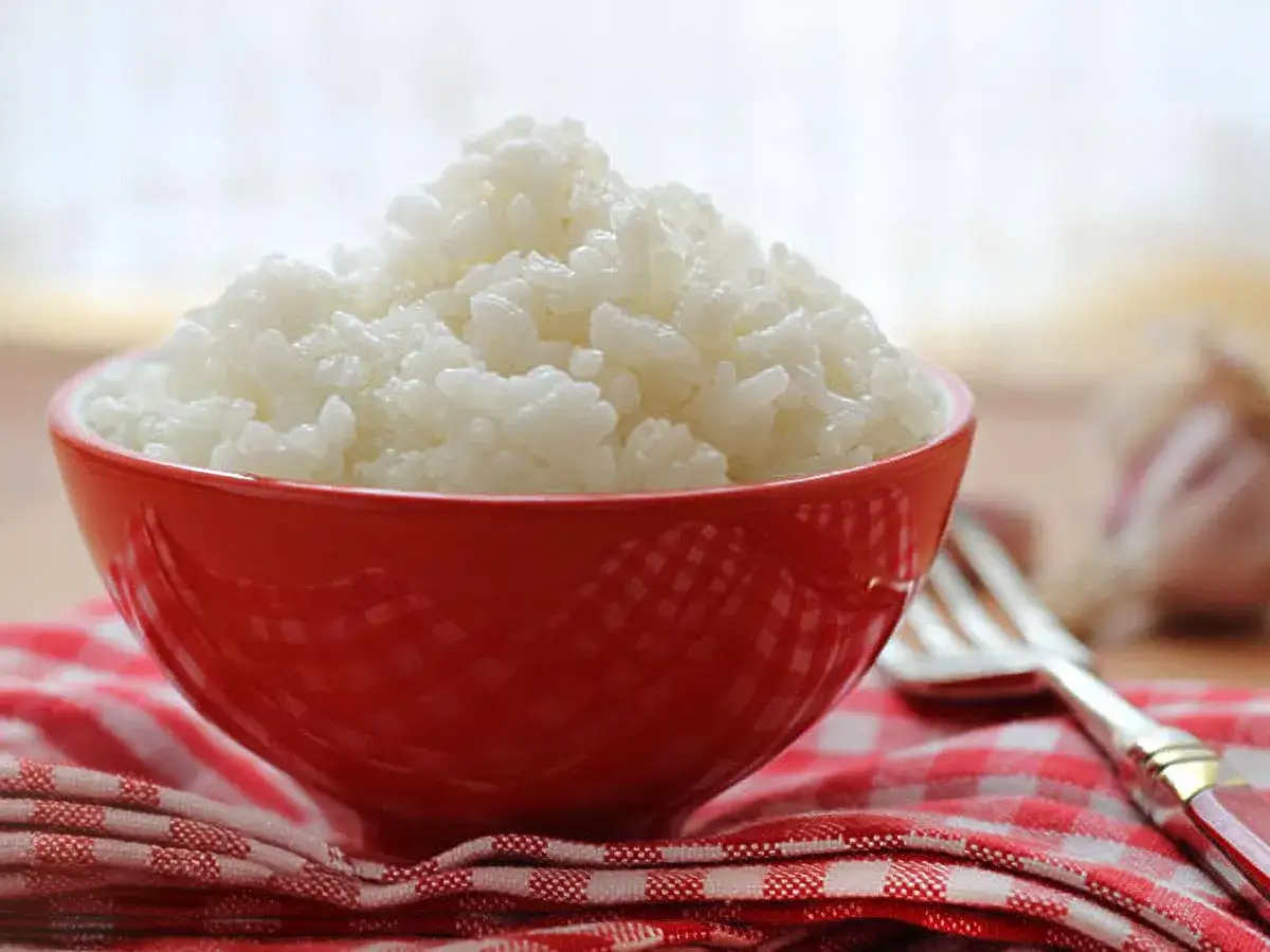 Un taz&oacute;n rojo lleno de arroz blanco esponjoso, listo para acompa&ntilde;ar cualquier comida.