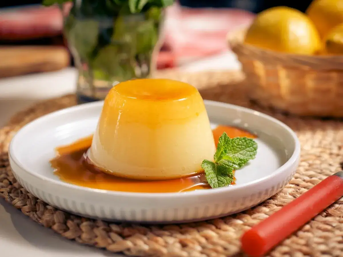 Delicioso flan de limón con caramelo líquido, decorado con menta fresca. Un postre refrescante y dulce.
