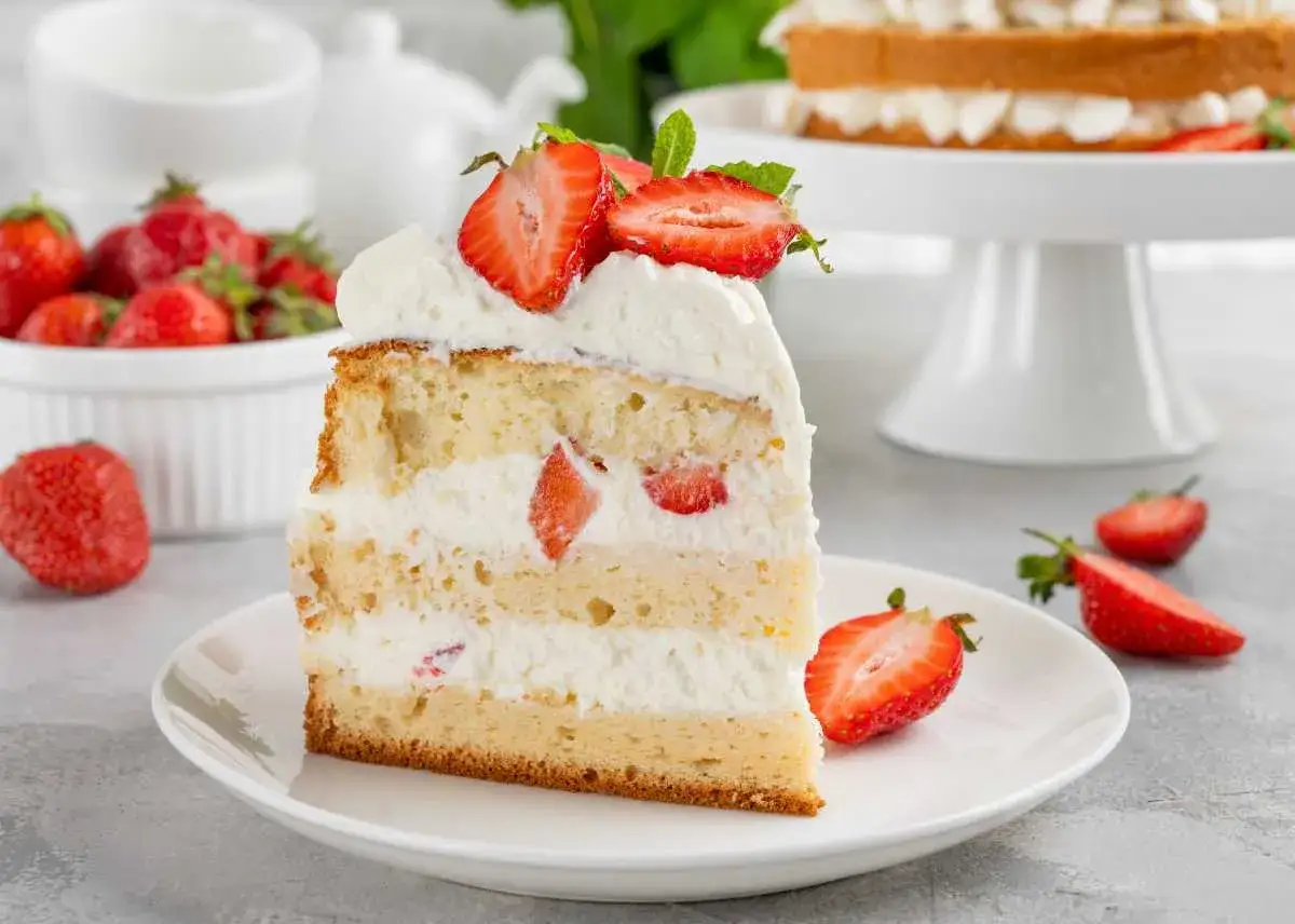 Porción de tarta de fresas con nata y queso Philadelphia, decorada con fresas frescas y menta.