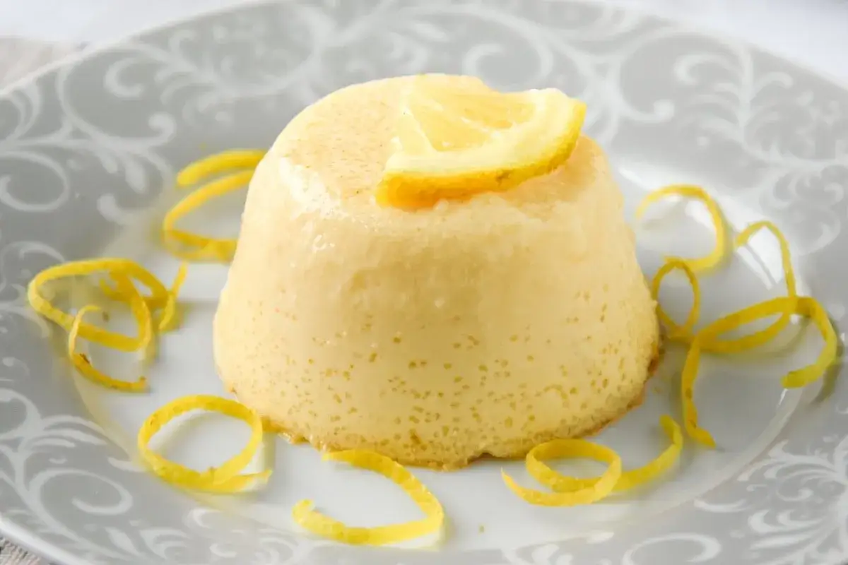 Delicioso flan de limón, coronado con una rodaja de limón y decorado con cáscaras de limón en espiral.