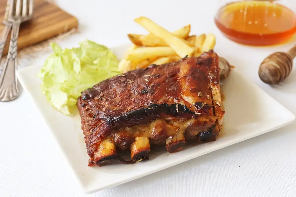 Costillas al horno jugosas y doradas, acompa&ntilde;adas de papas fritas crujientes y una hoja de lechuga fresca. Un fest&iacute;n para los sentidos.