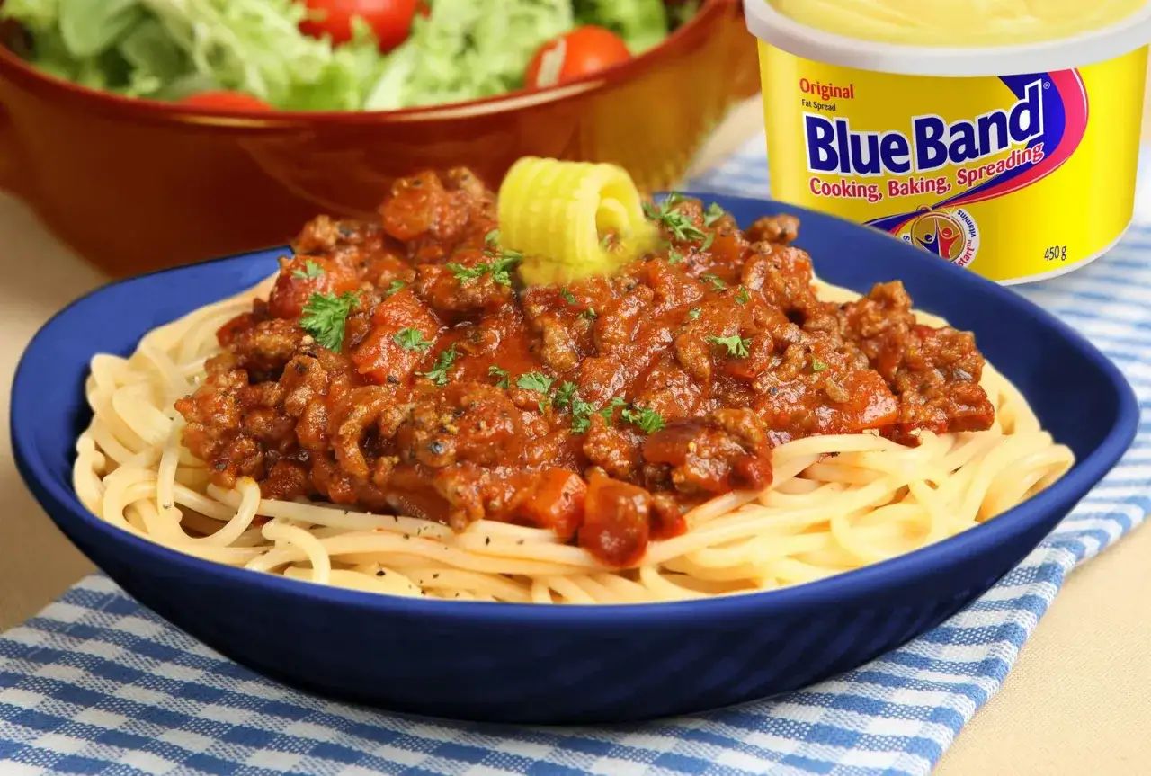 Espaguetis con una rica salsa de carne picada y tomate, coronados con una rodaja de mantequilla y perejil.