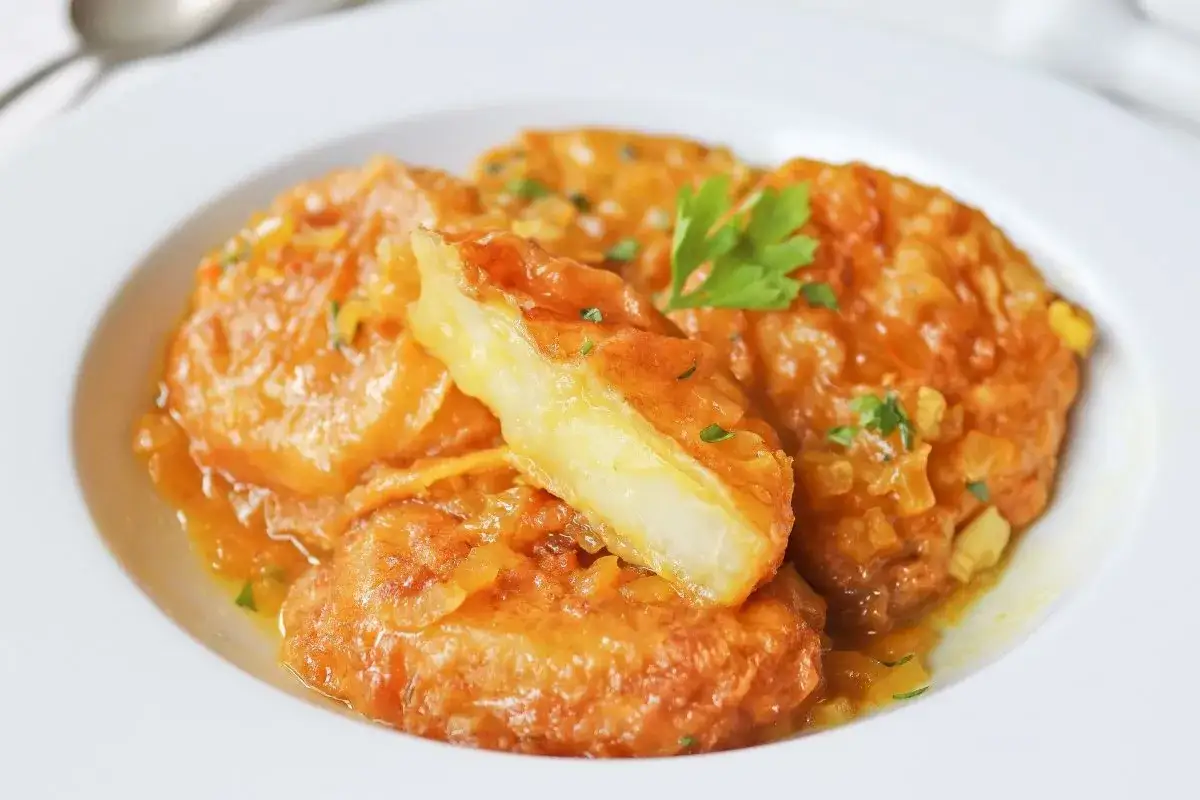 Patatas a la importancia, doradas y jugosas, servidas en un plato blanco con perejil fresco. Un manjar que demuestra la importancia de las patatas en la cocina.