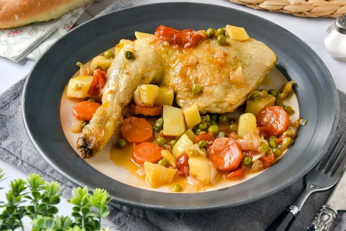 Un delicioso pollo a la jardinera con patatas, zanahorias y guisantes en una salsa sabrosa.