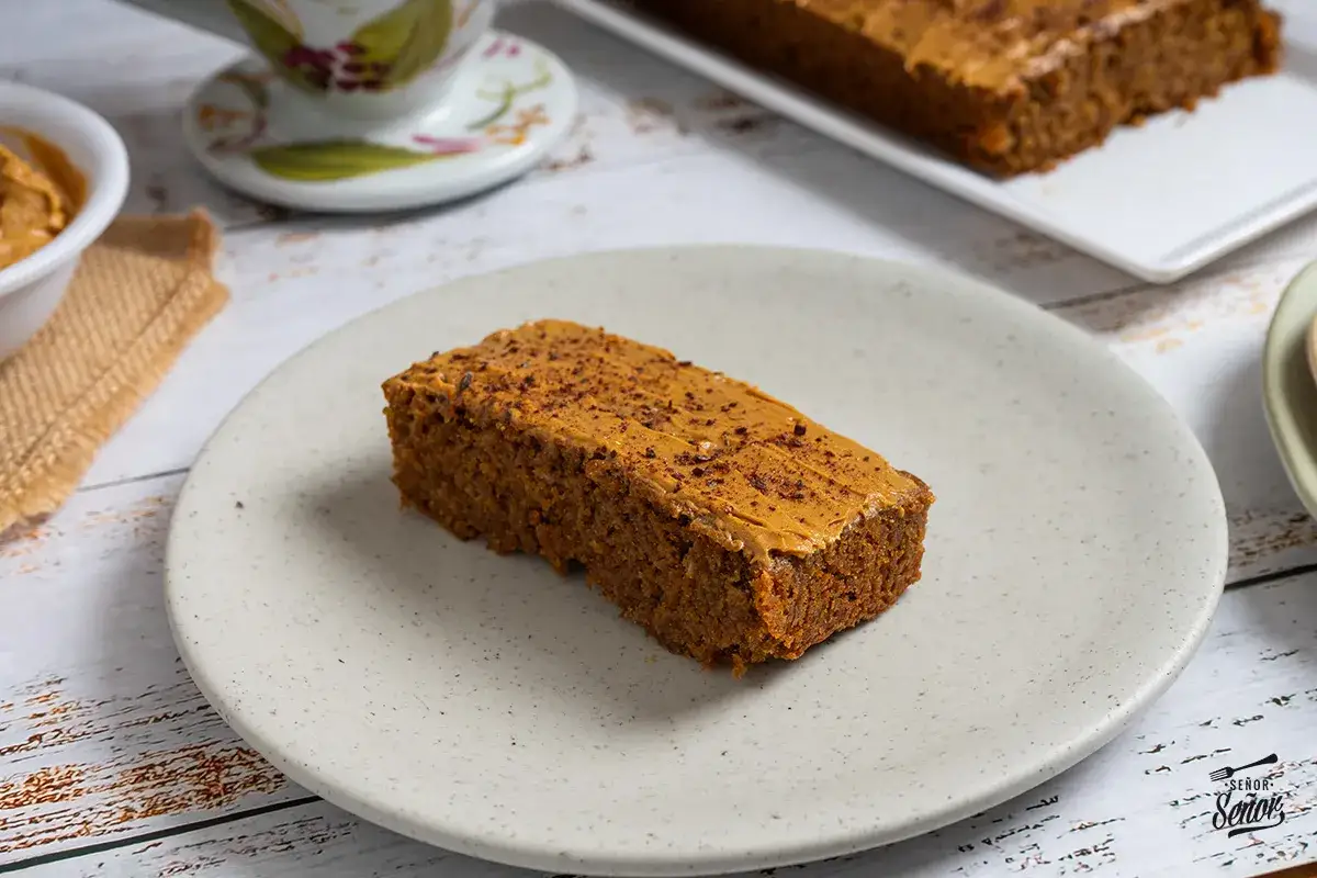 Un trozo de pa de pessic con cobertura de crema de cacahuete y espolvoreado con cacao.