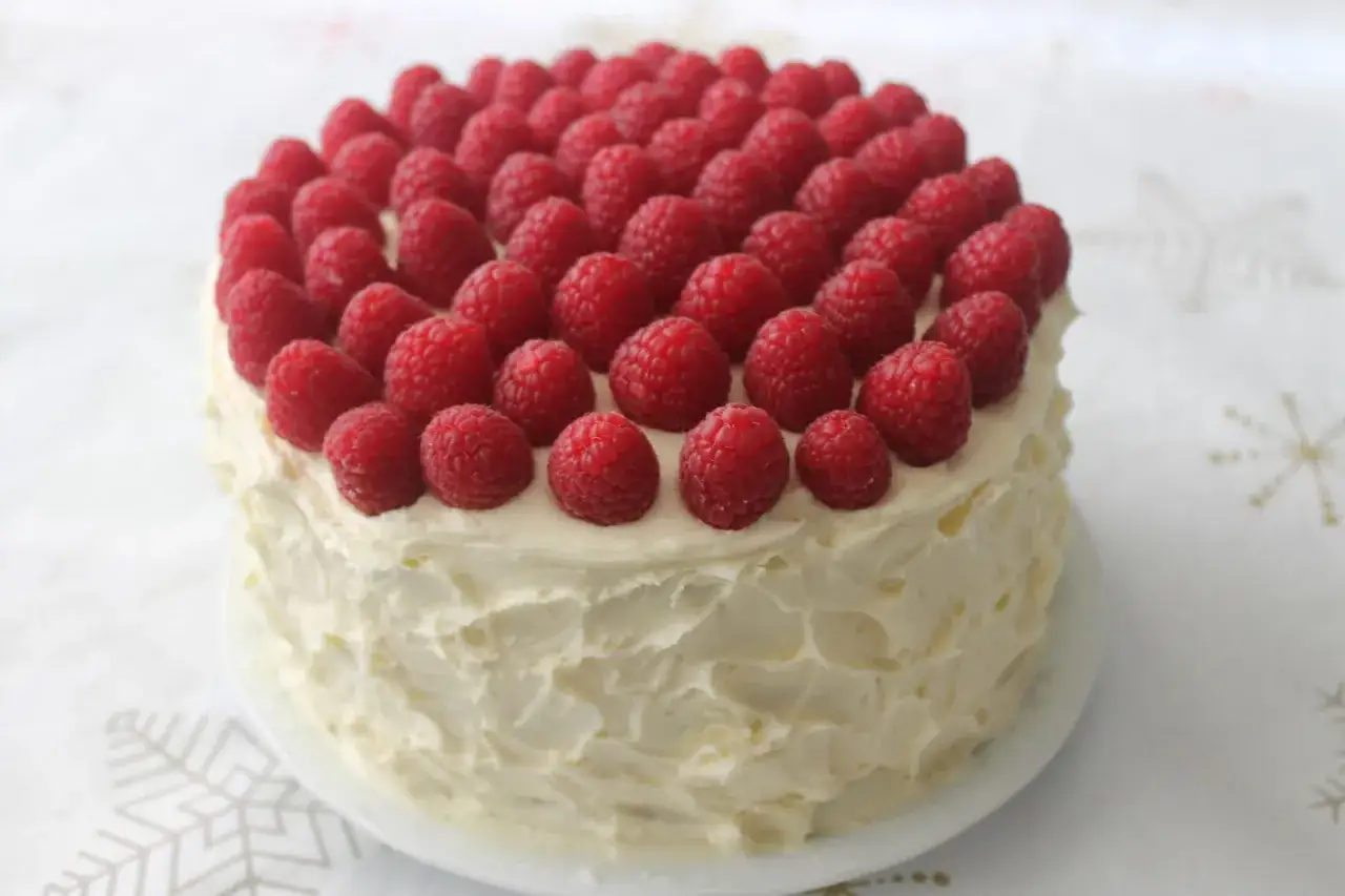 Tarta de chocolate blanco cubierta de crema y frambuesas frescas.
