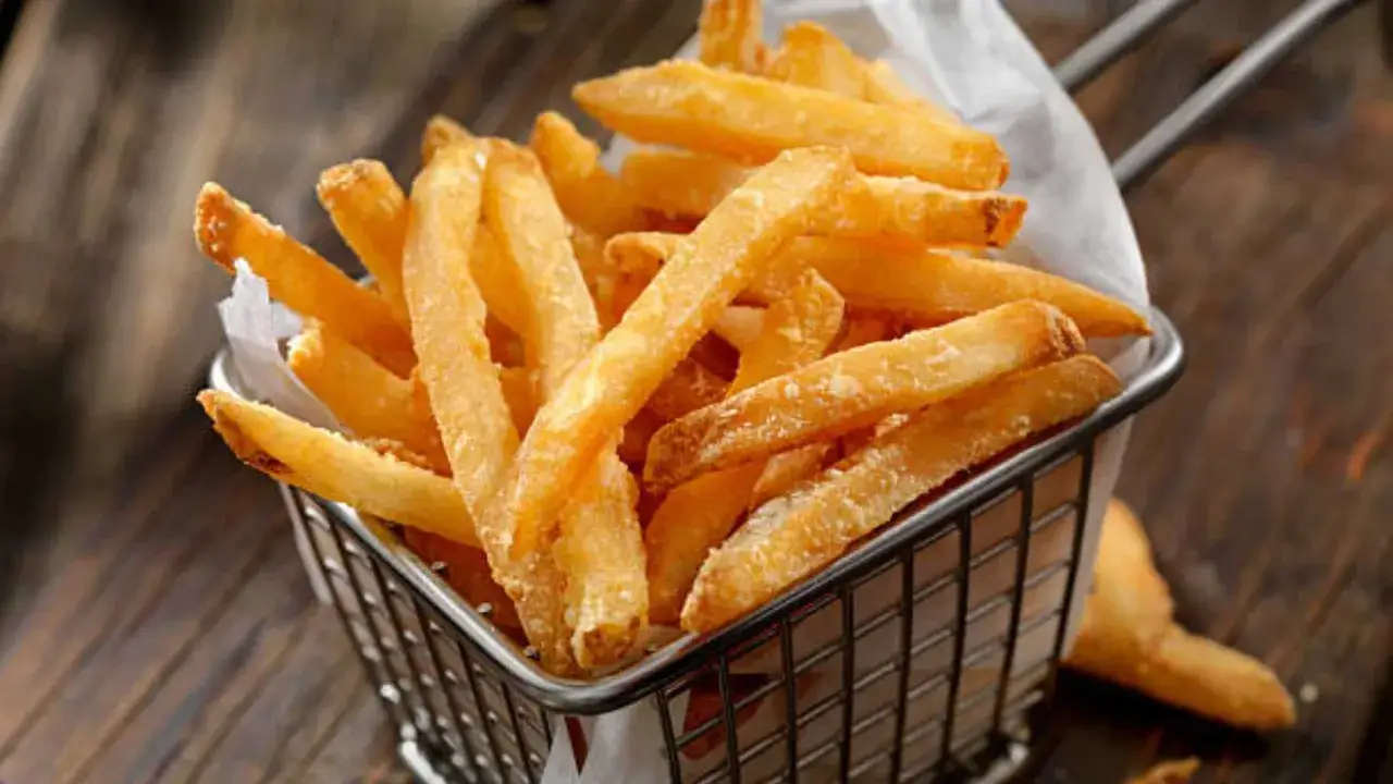 Cesta met&aacute;lica llena de patatas fritas doradas y crujientes, listas para ser disfrutadas.