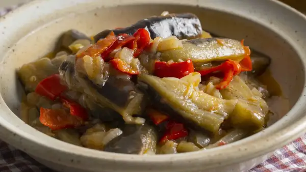 Berenjenas en escabeche, un plato casero con trozos de berenjena, pimientos rojos y cebolla en una salsa sabrosa.