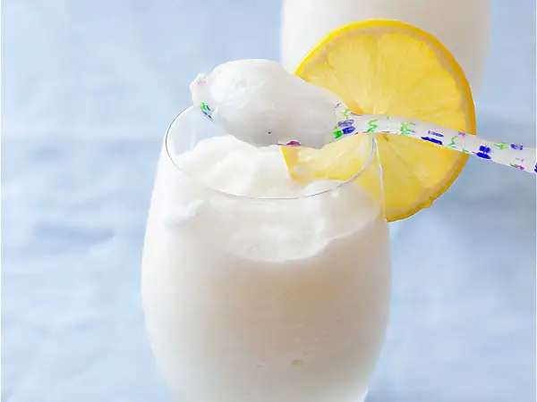 Refrescante sorbete de limón al cava, servido en copa con rodaja de limón y cuchara decorada.