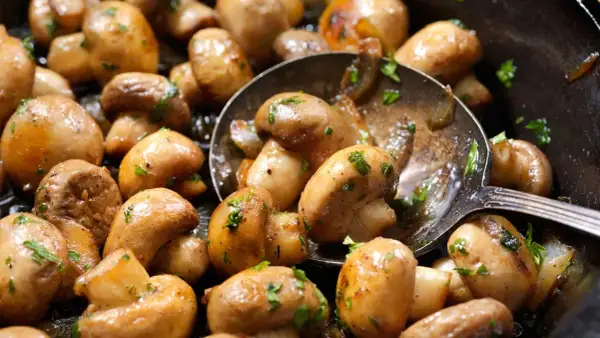 Champiñones dorados y jugosos, recién salidos de la freidora de aire, con perejil fresco picado. ¡Una delicia fácil y rápida!