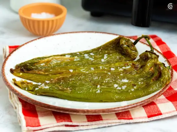 Pimientos verdes asados en freidora de aire, servidos en plato blanco con sal gruesa.