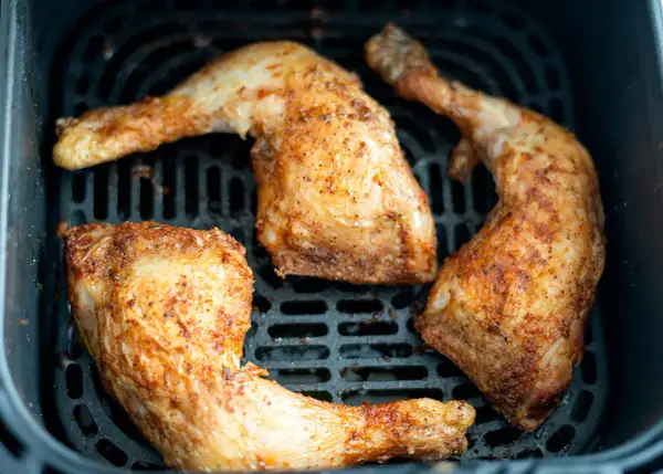 Muslos de pollo dorados y jugosos en la freidora de aire, listos para disfrutar.