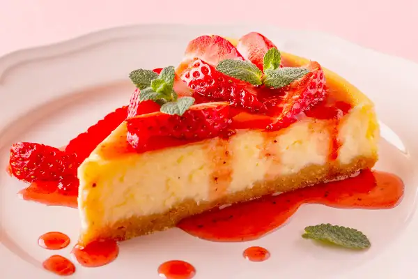 Deliciosa tarta de fresas con nata y queso Philadelphia, cubierta con salsa de fresa y hojas de menta.