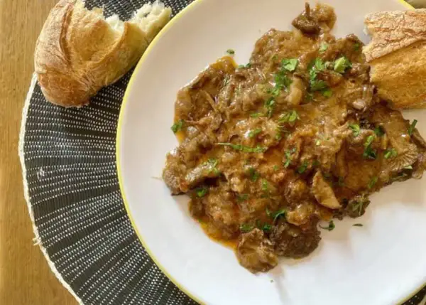 Delicioso fricando de ternera con trozos de pan crujiente, listo para disfrutar.