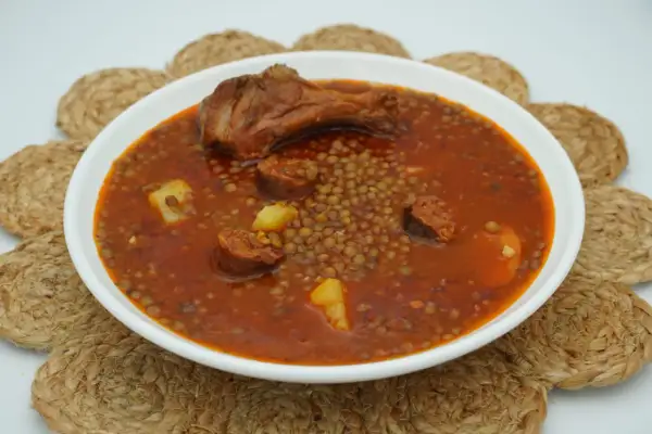 Un plato humeante de lentejas con chorizo, patatas y un muslo de pollo. Un manjar casero listo para disfrutar.