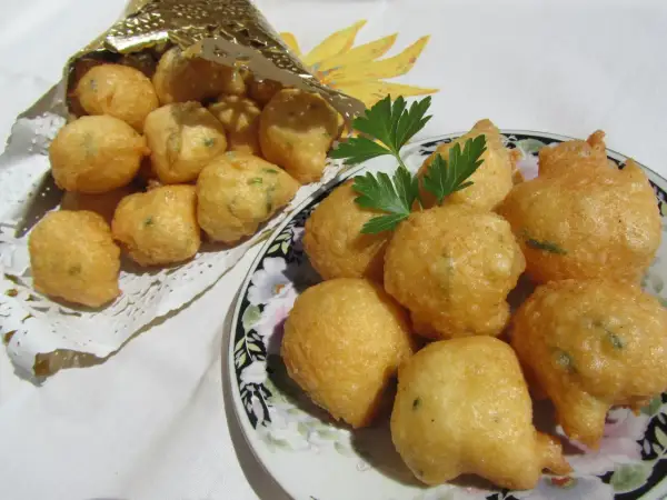 Buñuelos de bacalao hechos en Thermomix, dorados y crujientes, servidos en un plato y en un cono dorado.