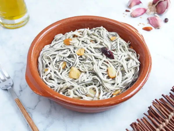 Deliciosas gulas al ajillo en cazuela de barro, con láminas de ajo dorado y un toque picante.