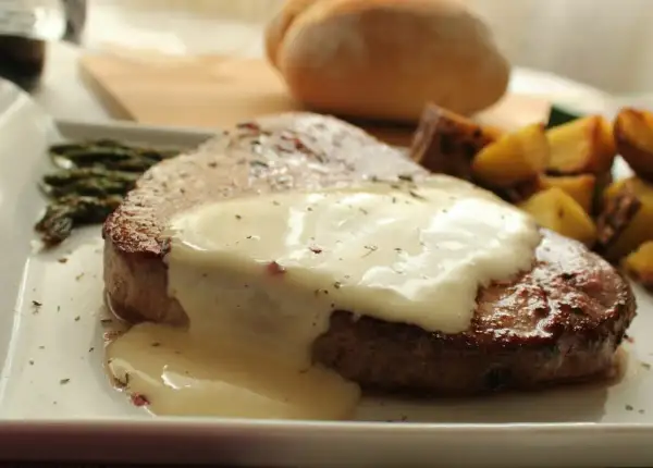 Tierna ternera en salsa cremosa, acompañada de espárragos y patatas asadas. Un plato principal delicioso.