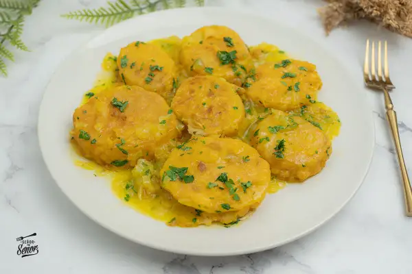 Patatas a la importancia, doradas y tiernas, bañadas en una salsa amarilla con perejil picado. Un plato que demuestra la importancia de las patatas en la cocina.
