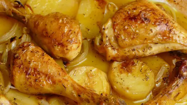 Pollo al horno con patatas, dorado y jugoso, con hierbas aromáticas y cebolla. Un plato casero irresistible.