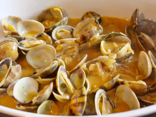 Un plato humeante de almejas a la marinera, con su salsa dorada y trozos de ajo. ¡Un manjar!