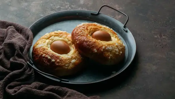 Dos monas de Pascua esponjosas, cubiertas de azúcar, con un huevo cocido incrustado en cada una, listas para disfrutar.