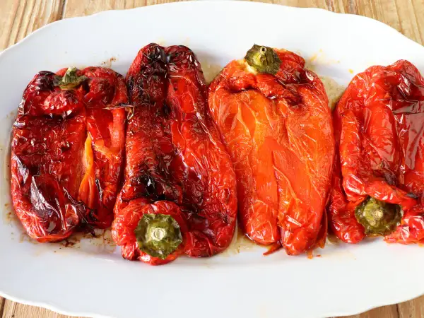 Pimientos rojos asados en freidora de aire, con piel arrugada y un brillo apetitoso.