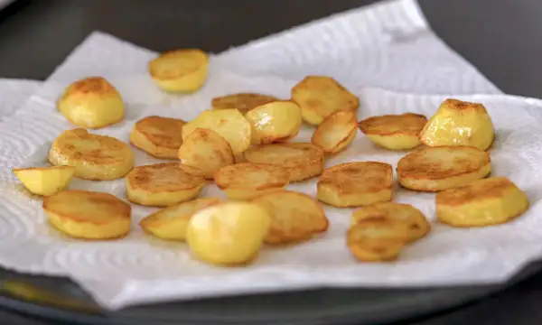 Patatas al horno doradas y crujientes, recién salidas del horno y reposando sobre papel absorbente. ¡Listas para disfrutar!
